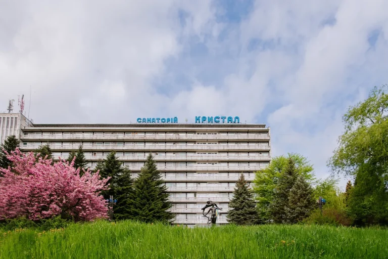Санаторій Кристал у Трускавці серед зеленої трави і квітучих дерев