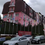 Фасад отеля Royal Grand с флагами и автомобилями на улице в Трускавце