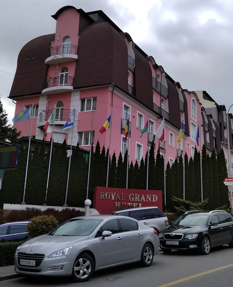 Фасад отеля Royal Grand с флагами и автомобилями на улице в Трускавце