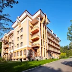 Фасад санаторію «Кришталевий Палац» у Трускавці на тлі ясного неба та зелені