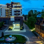 Фасад санаторію Mirotel Resort & SPA у Трускавці ввечері з підсвіткою і парковкою