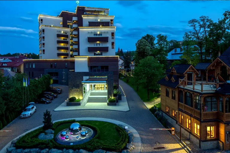 Фасад санаторію Mirotel Resort & SPA у Трускавці ввечері з підсвіткою і парковкою