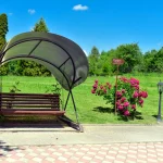 Гойдалка під навісом на території санаторію «Південний» у Трускавці з квітучими кущами