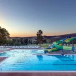 Відкритий басейн з гірками курортного комплексу Rixos-Prykarpattya у Трускавці на заході сонця