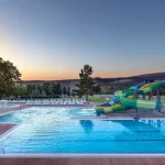 Відкритий басейн з гірками та шезлонгами у курортному комплексі Rixos-Prykarpattya Трускавець
