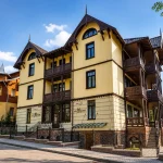 Вілла «Моцарт» у Трускавці з балконами та дерев’яним декором, фасад під блакитним небом